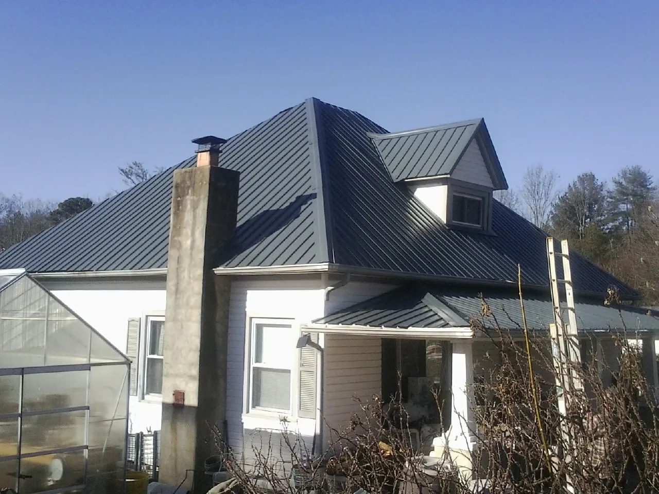 Dark blue standing seam metal roof on a white farmhouse with dormer — Slate & Tile Roof Repair by Roofing Brothers in Crab Orchard