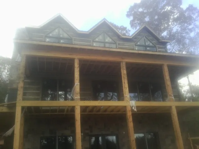 Dormers and porch framing on a large log home under construction — Roof Coating work by our crew in Crab Orchard